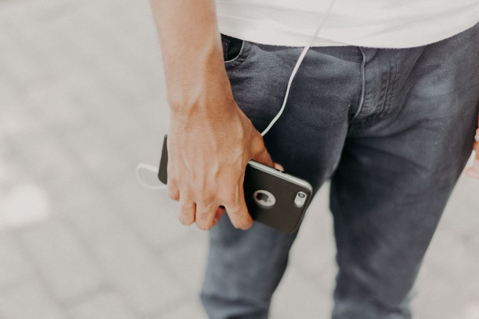 A resident walking through a building corridor wearing earbuds and glancing at a phone