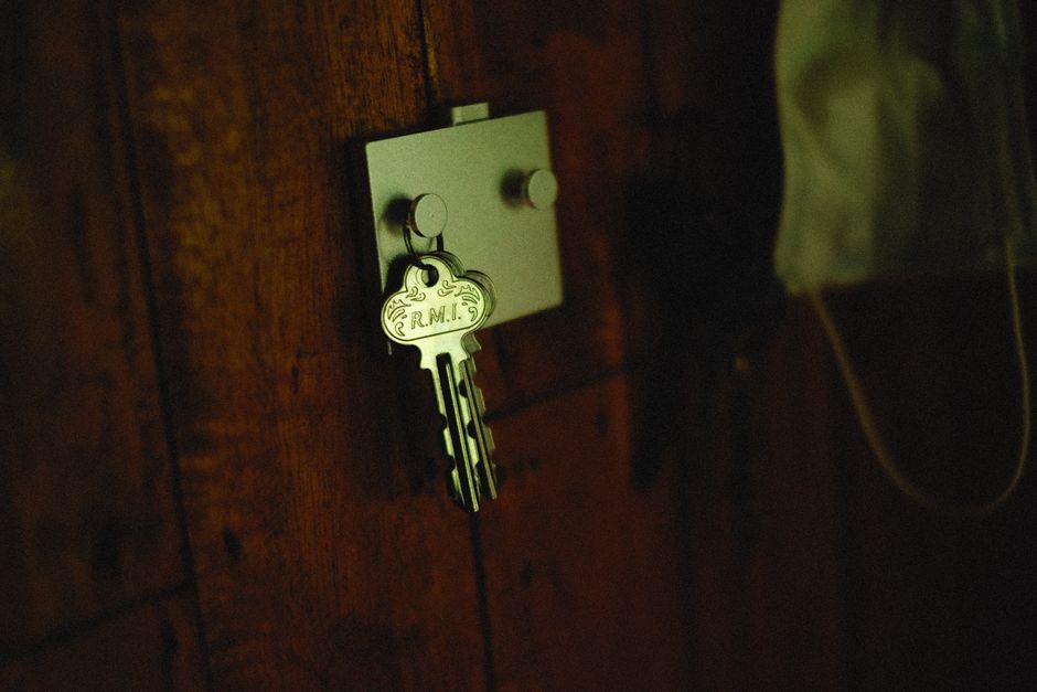 House keys hanging on a small hook mounted beside an apartment entry door