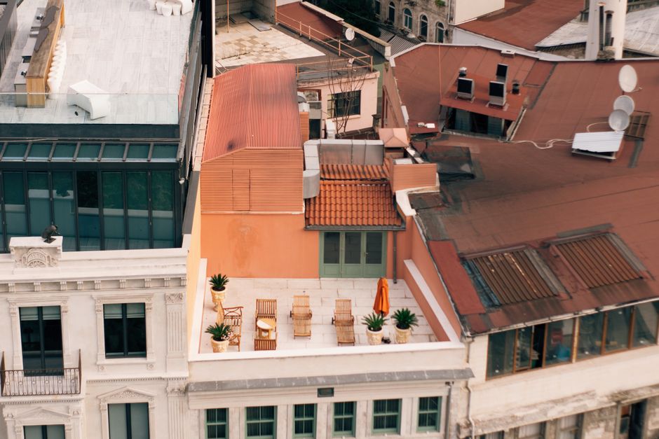 A shared apartment building rooftop terrace with lounge seating and open deck space overlooking the city