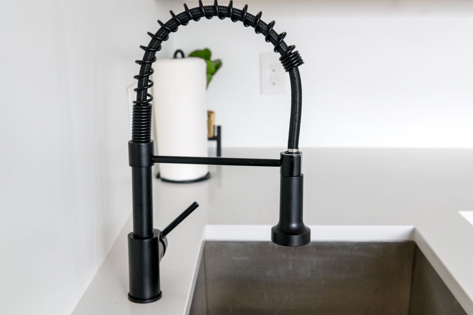 The pipes and cabinet interior under a kitchen sink, the kind of spot checked with a flashlight for leaks and water stains du