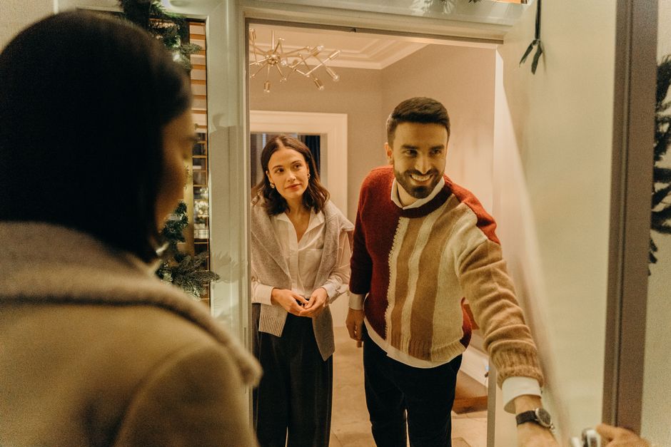 Two neighbors standing at an apartment doorway having a calm, face to face conversation