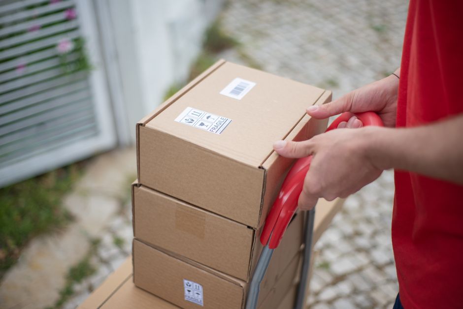 Cardboard delivery packages stacked on shelves in an apartment mailroom