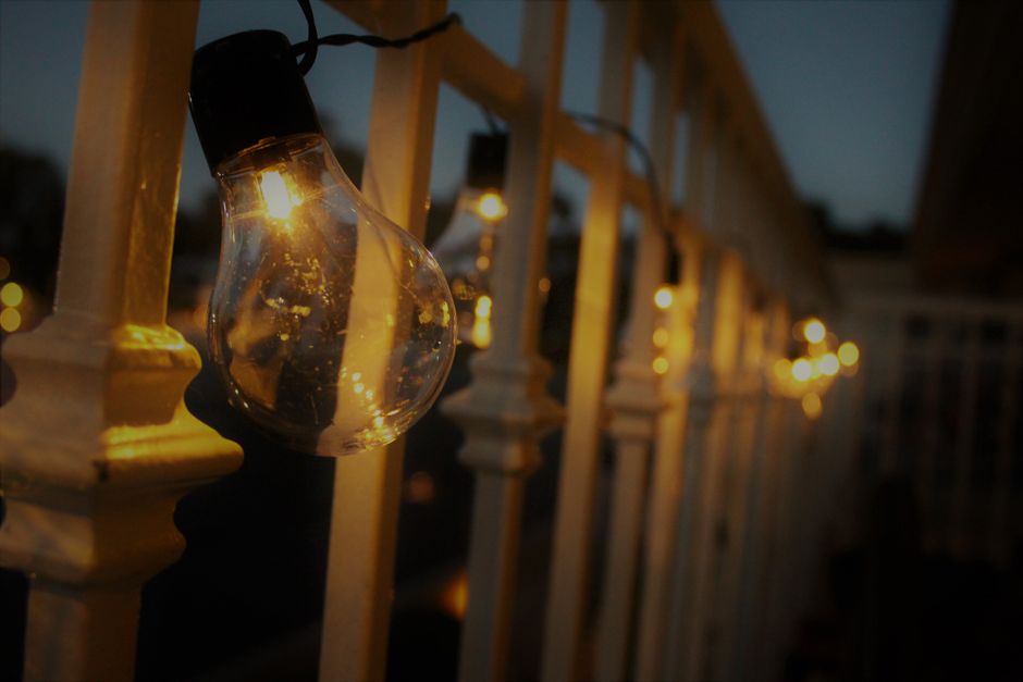 An outdoor patio lit by string lights on a warm summer evening