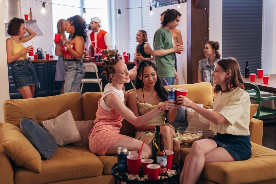A small group of friends gathered and laughing together in a cozy apartment living room during an evening get-together