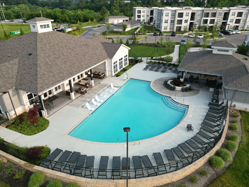 A swimming pool on an apartment building deck surrounded by lounge chairs on a sunny day