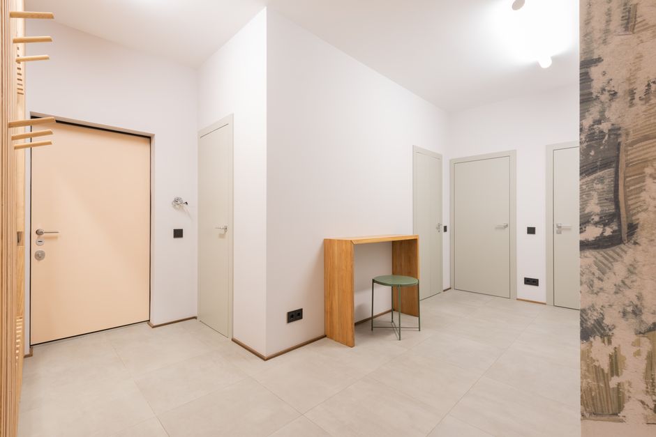 A quiet residential apartment hallway lined with unit doors, the shared space where arriving and departing guests can carry n