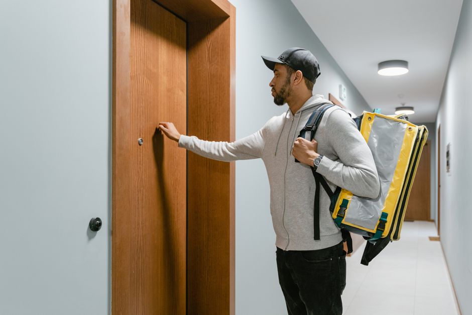A person knocking on a neighbor's apartment door to introduce themselves during their first week in the building.
