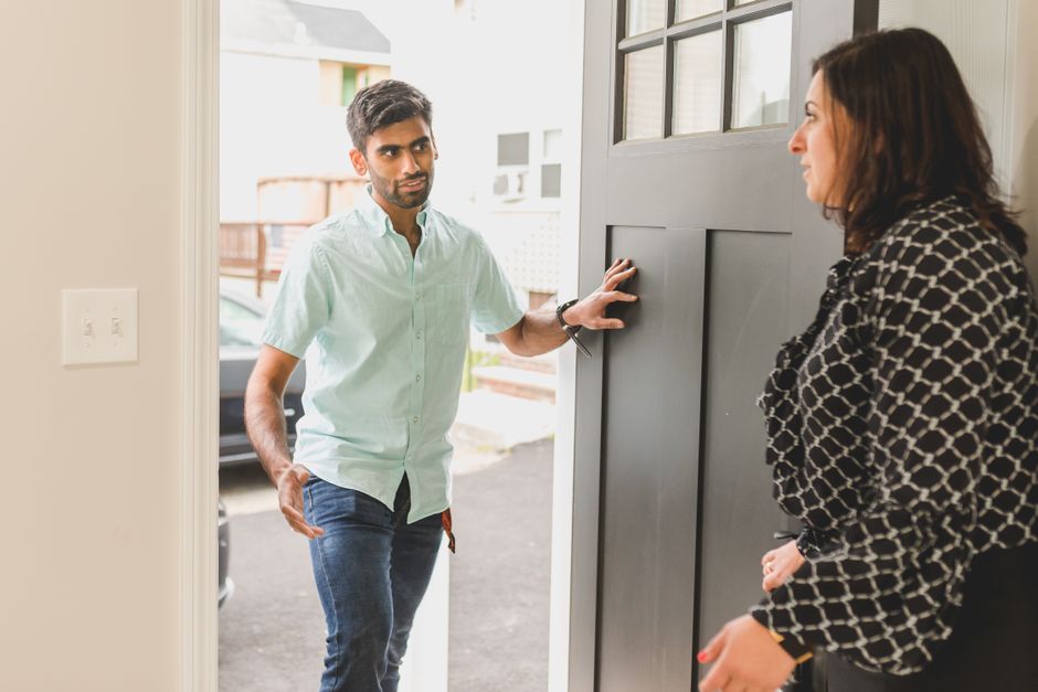 Two people having a calm, direct conversation at an apartment doorway