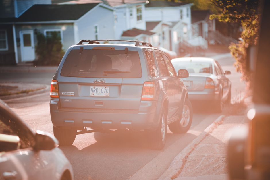 Two cars parked in a residential driveway between neighboring houses