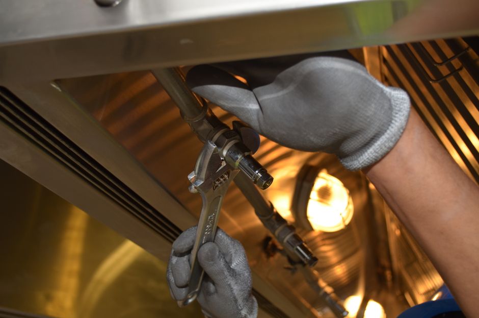 A maintenance technician works on a leaking kitchen sink under the cabinet after a clear, specific repair request.