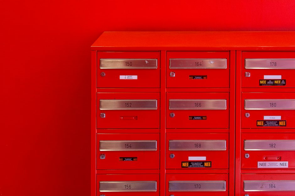 A wall of numbered resident mailboxes in an apartment building lobby mailroom