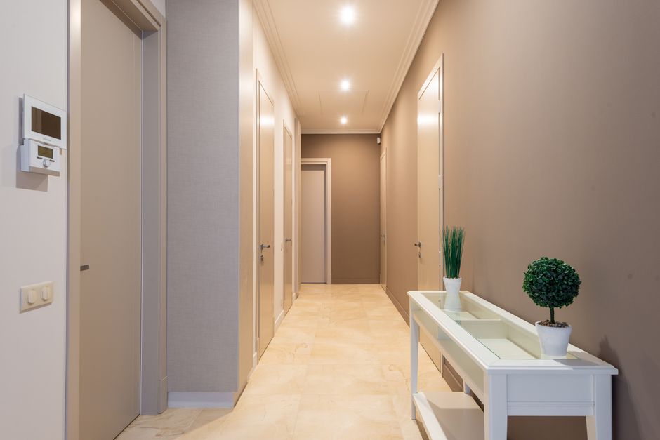 A residential building hallway lined with unit doors, the setting for a friendly greeting to an unfamiliar face