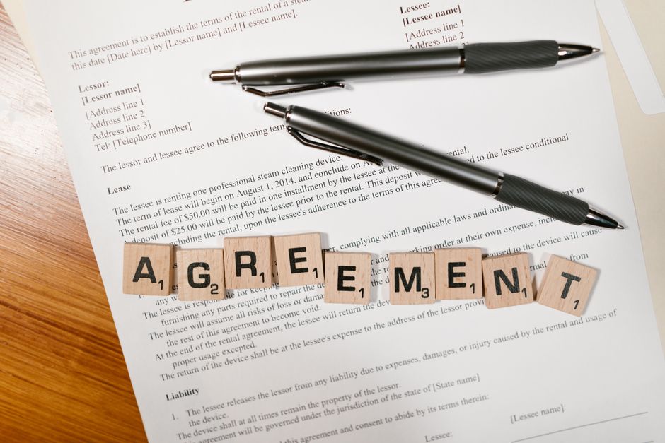 Two people signing a written sublease agreement on a table with a pen