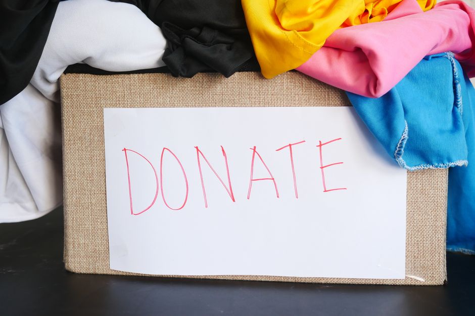 A cardboard box packed with neatly folded clothes set aside for donation during a category-by-category declutter