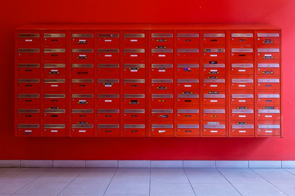 A row of numbered apartment mailboxes with name labels in a building lobby