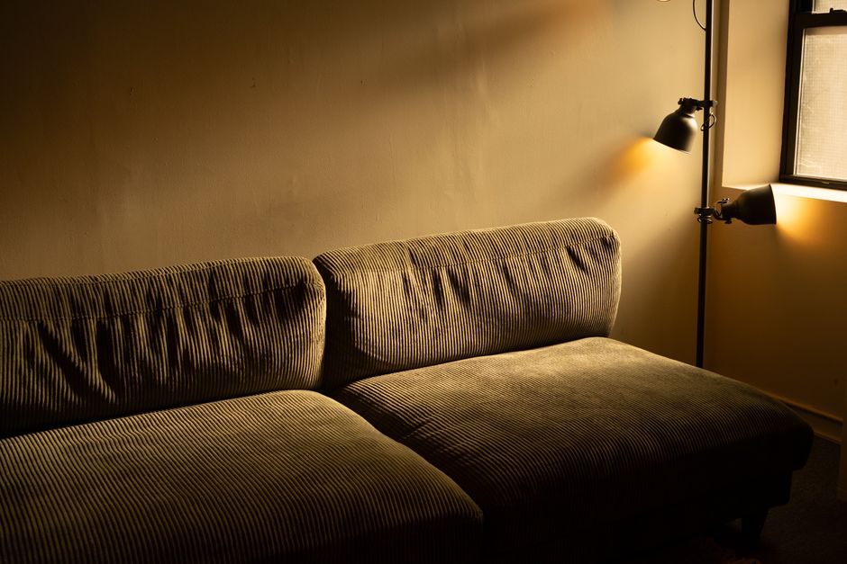A floor lamp casting soft warm light in a cozy apartment living room in the evening