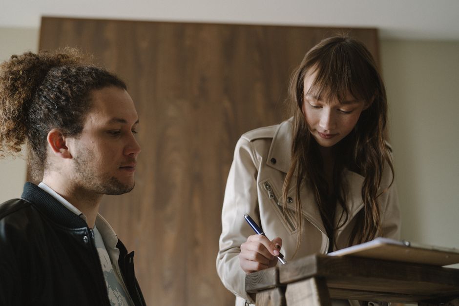 Two roommates sitting at a table reviewing and signing a lease and roommate agreement together