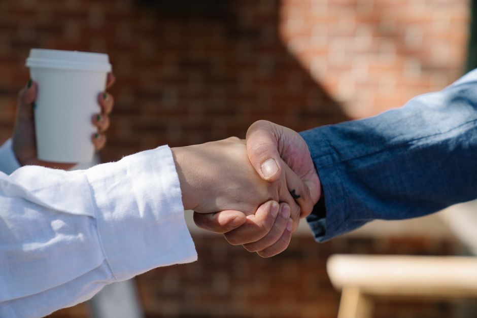 Two neighbors shaking hands and introducing themselves in an apartment building hallway