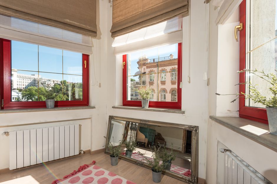 A cast iron radiator mounted beneath a window in an older apartment unit