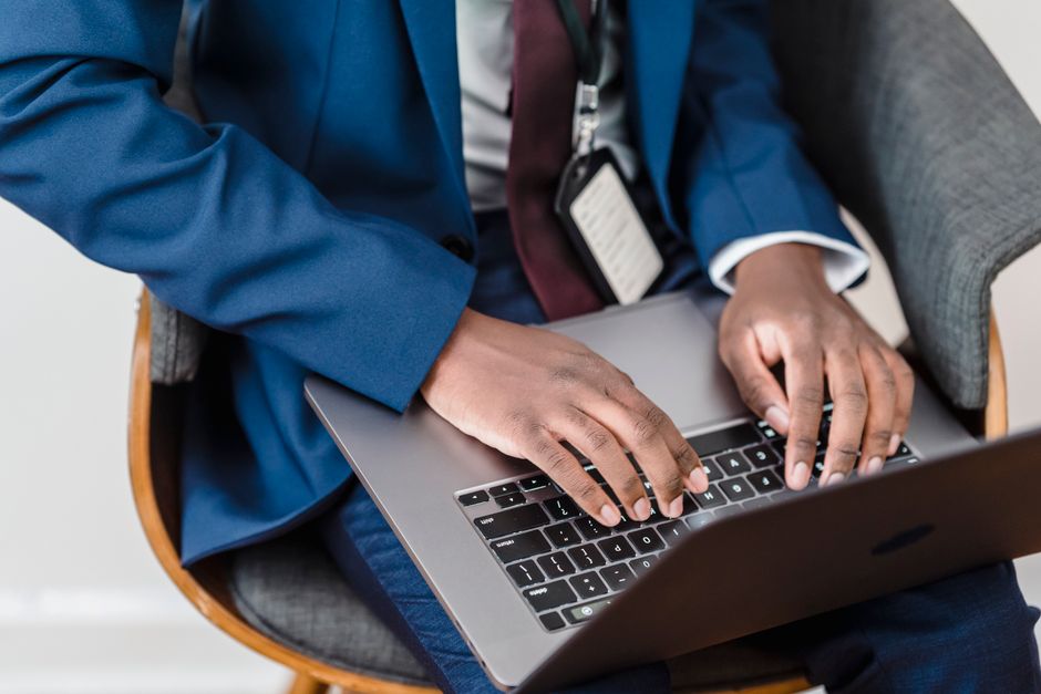 A person seated at a desk composing a carefully worded email on a laptop keyboard
