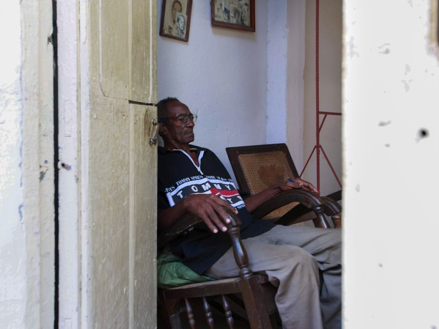 An older resident standing in the doorway of their apartment, the kind of neighbor a friendly welfare check-in can help