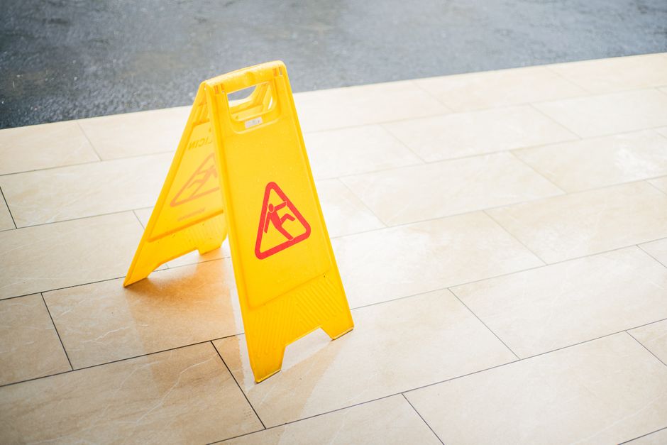 A yellow wet floor caution sign standing on a freshly mopped lobby floor
