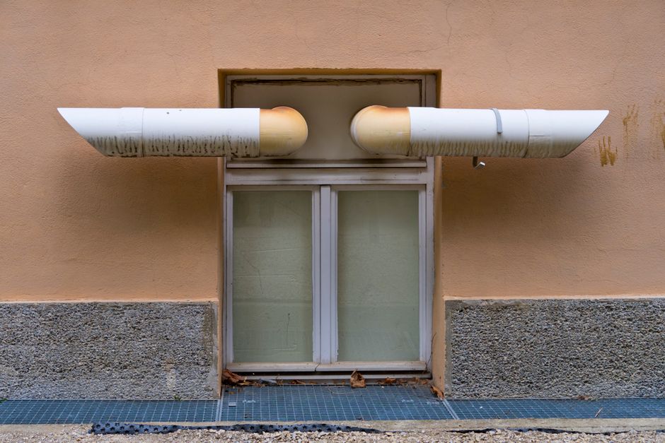 A metal HVAC air vent grille mounted on an apartment wall, one of the main paths sound travels between units