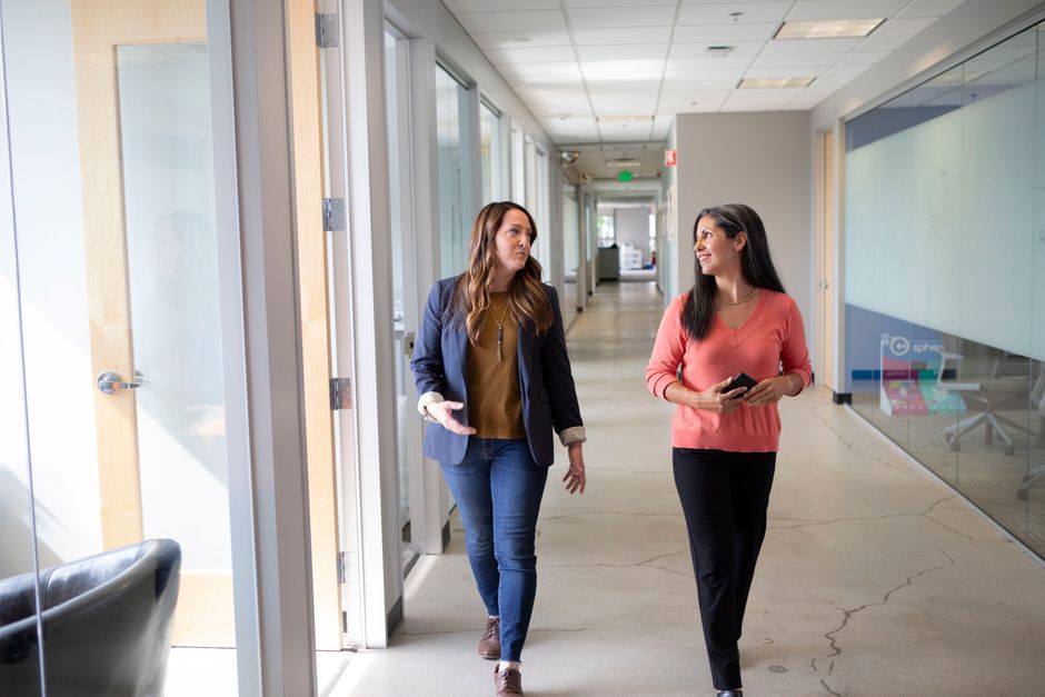 Two neighbors pausing to chat in an apartment building hallway near their unit doors