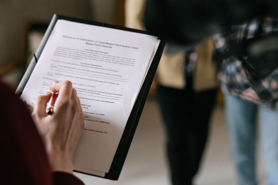 A person signing a rental lease agreement at a table with a pen, representing the option to renew