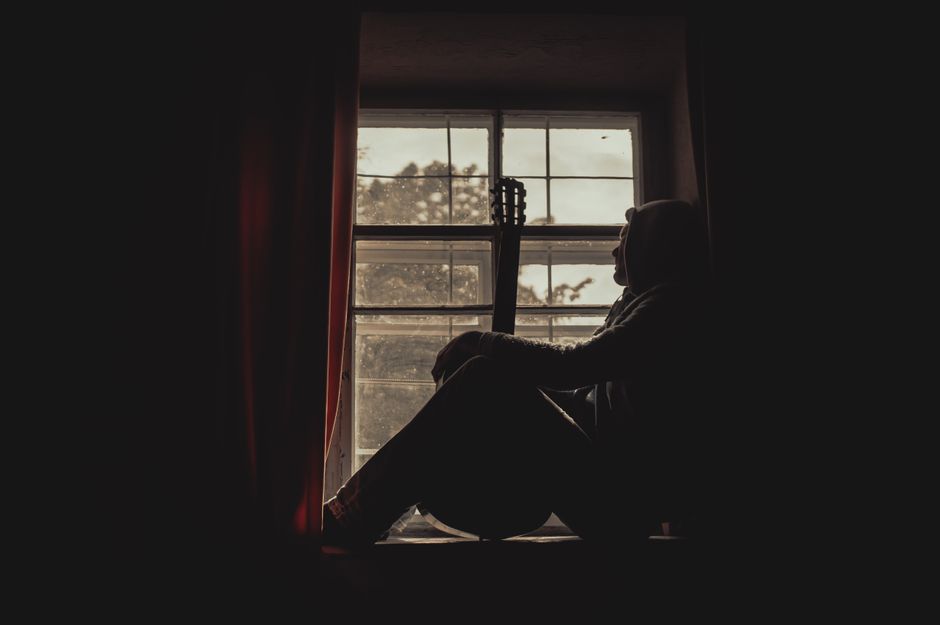 A person sitting calmly by an apartment window at home, choosing to let a minor conflict go.