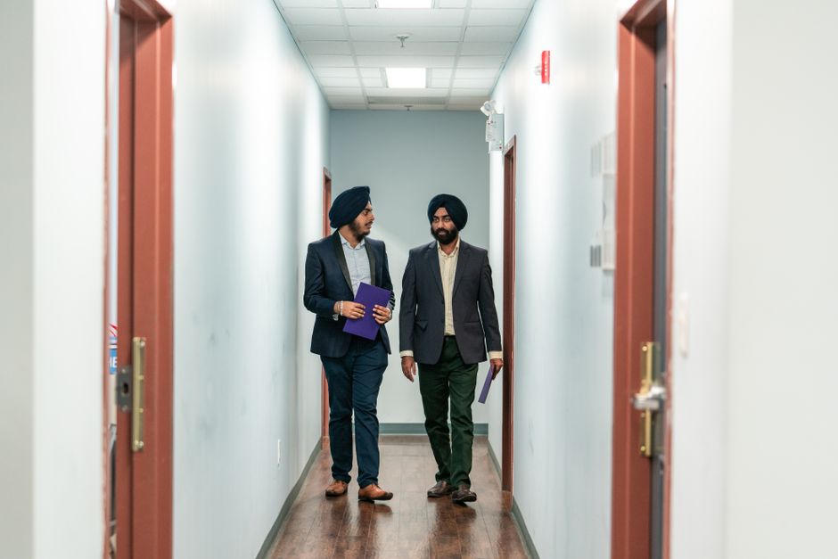 Two people having a calm face-to-face conversation in an apartment hallway, the kind of direct talk that can surface the real