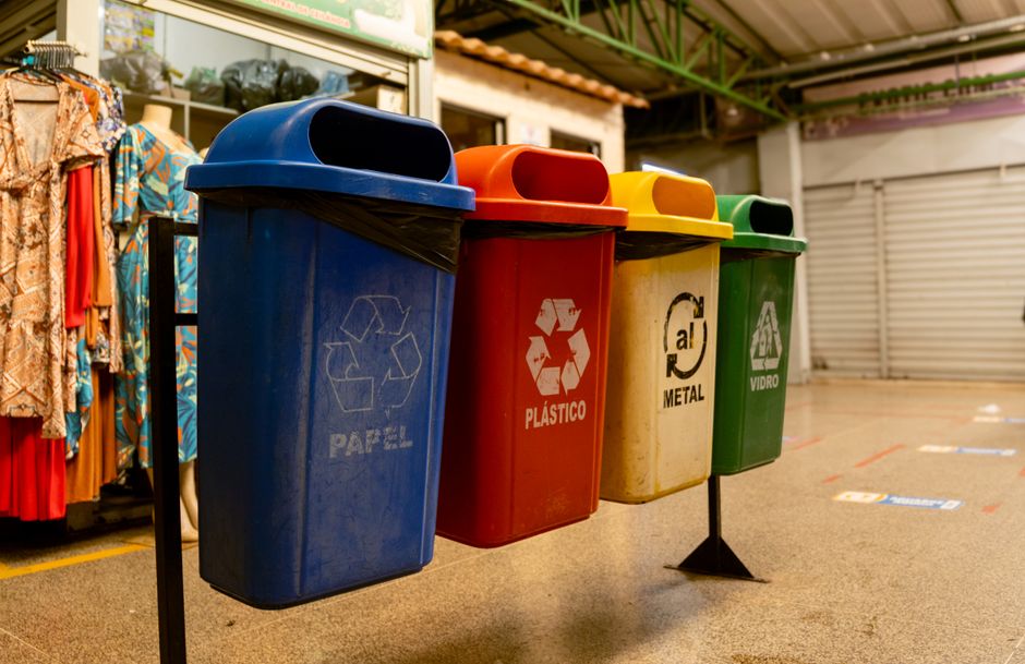 Rows of labeled recycling bins for separating paper, plastic, glass, and metal in an apartment building