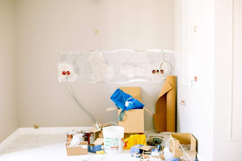 A putty knife applying spackling paste to fill a small nail hole in a wall before repainting.