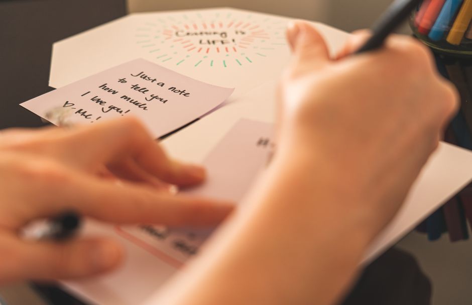 A short handwritten note on a folded piece of paper, ready to leave for a neighbor