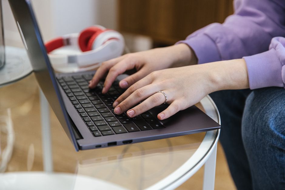 A resident sitting at a desk composing a calm, specific maintenance request email on a laptop.