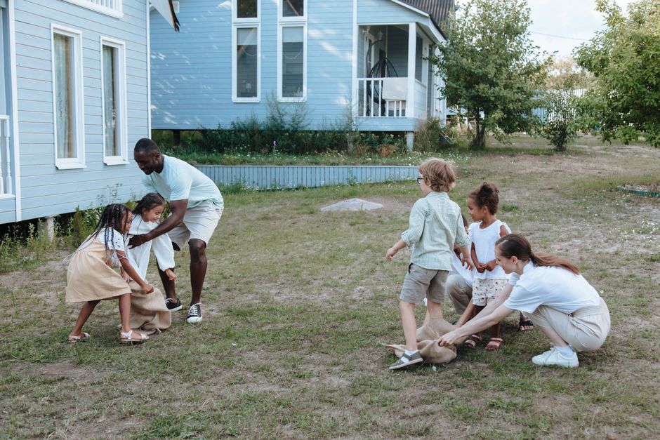 Two young children playing together on the grass of a suburban front yard