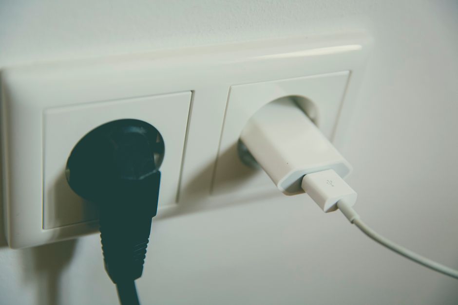 A phone charger plugged into a wall outlet to test whether the outlet works