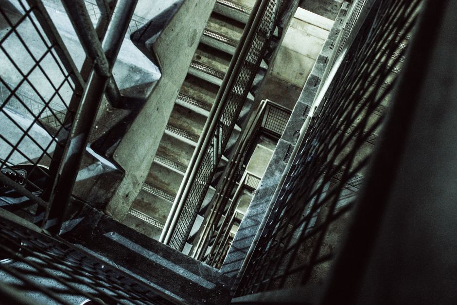 An empty apartment building stairwell with concrete steps and metal handrails, kept clear of clutter