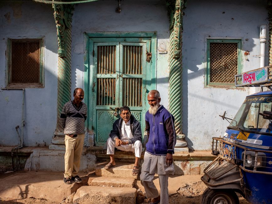 Residents sitting on the front steps of a building chatting on a summer evening