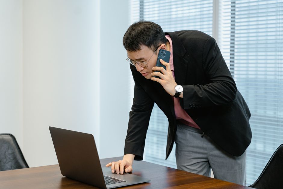 A person sitting at home holding a phone to their ear while making a call.