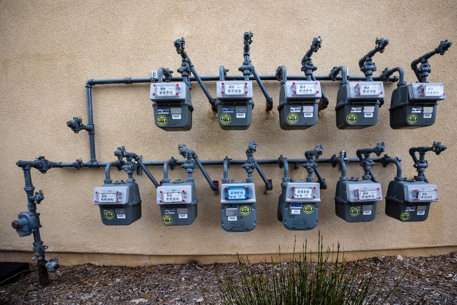 Close up of residential gas and electric utility meters mounted on an exterior apartment wall