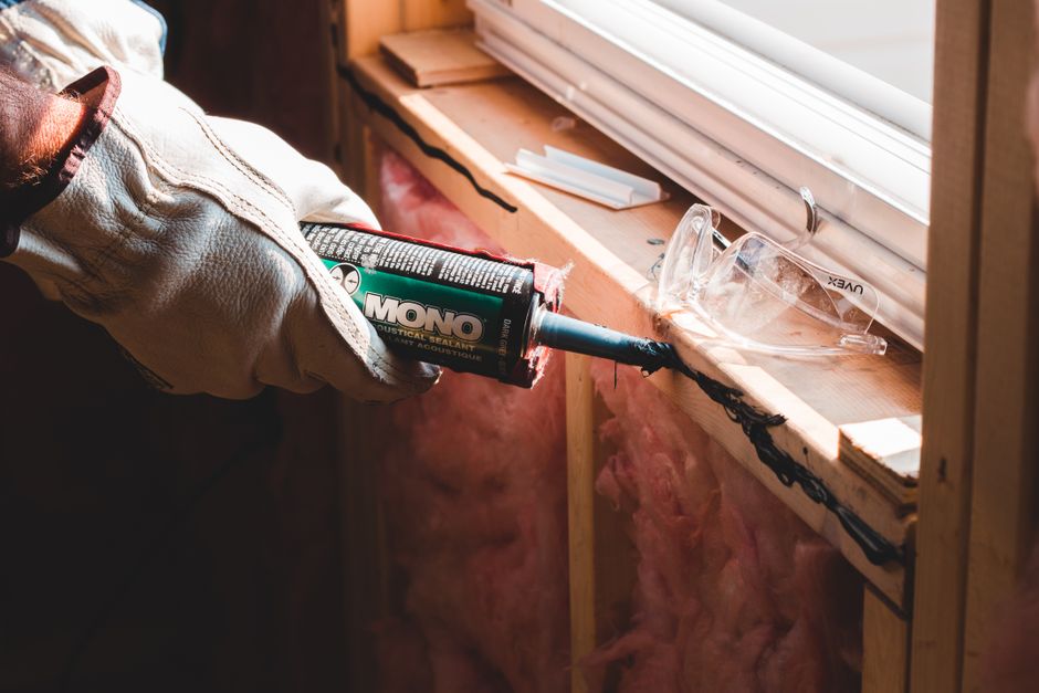 Insulating film and weatherstripping being fitted around an apartment window frame in winter
