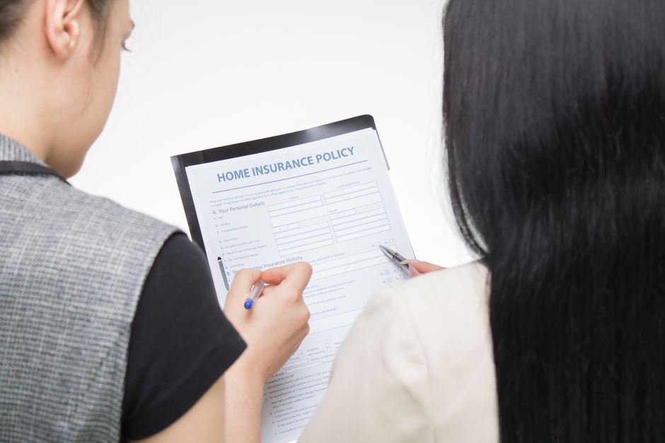 A person reading an insurance policy document at a kitchen table
