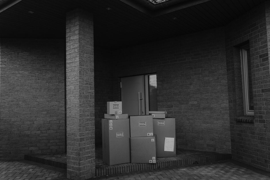 Cardboard delivery packages stacked near the entrance of an apartment building lobby