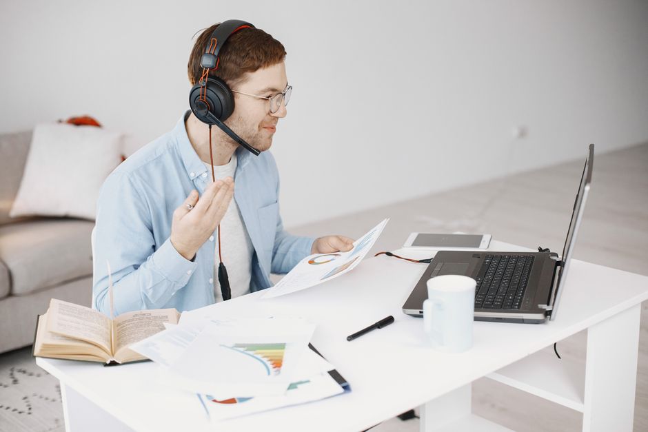 A remote worker wearing a headset while on a video call at a home office desk